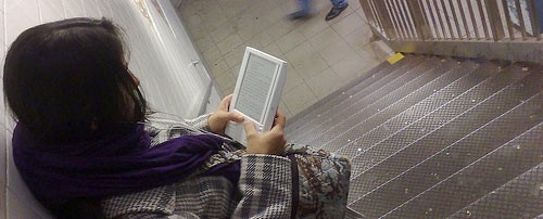 Chica leyendo un Kindle en la estación 86, USA.